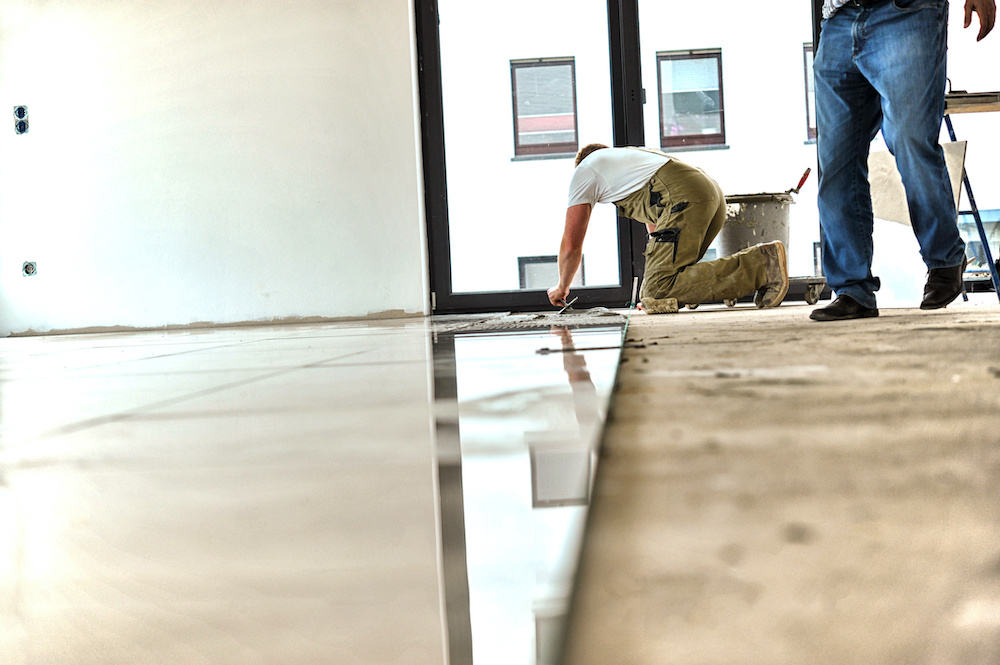 A man cleans water off a half-finished floor.