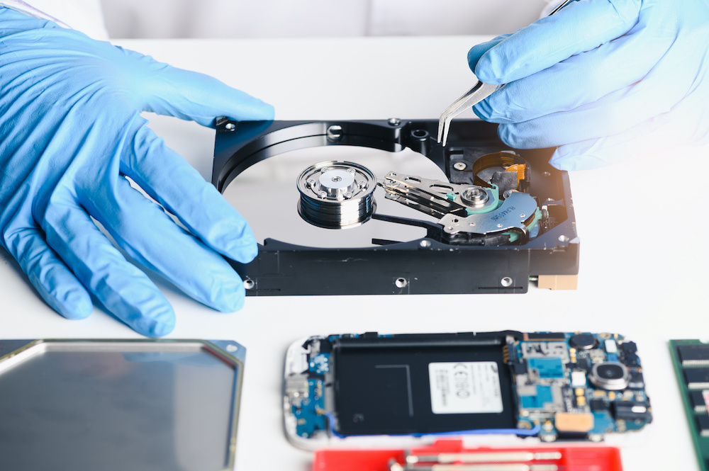 A professional works on data recovery, wearing blue gloves.
