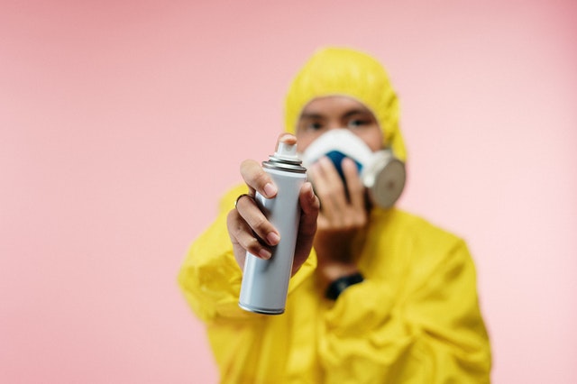 A person is spraying disinfectant while wearing a hazmat suit