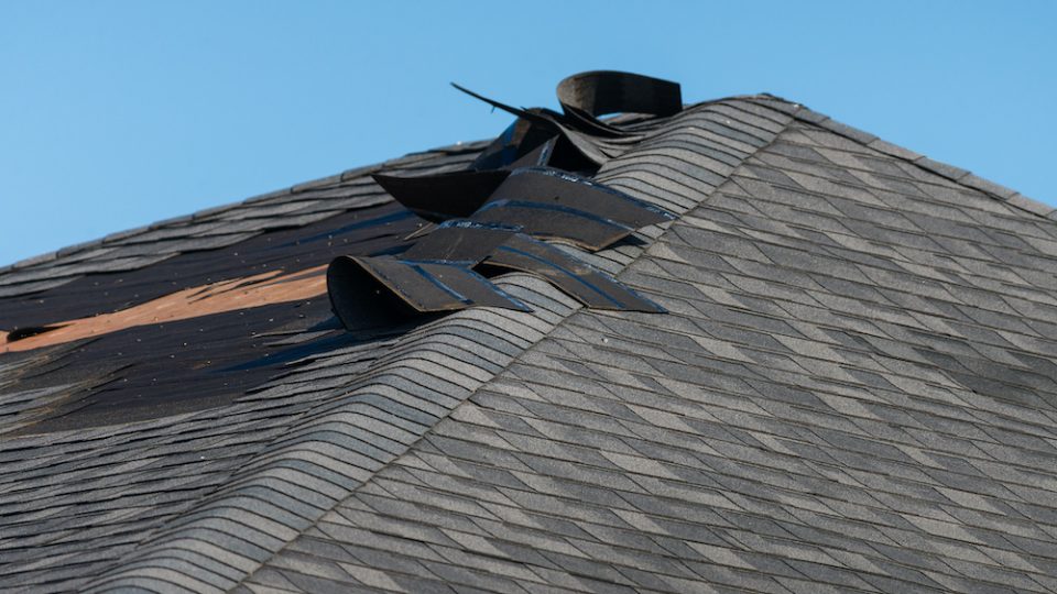 Damaged roof with loose shingles